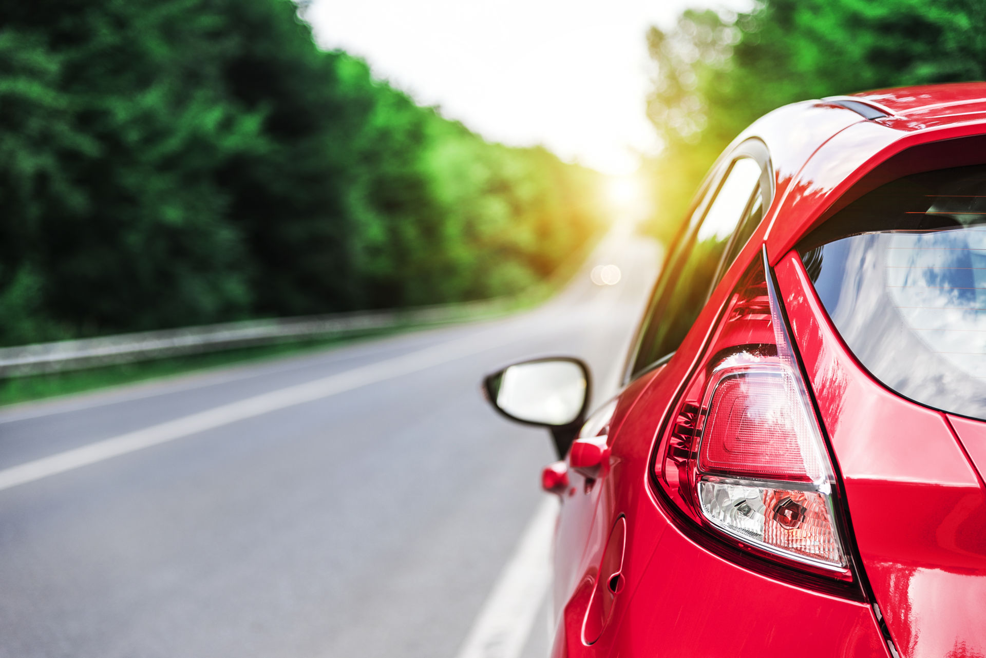 punainen auto takaapäin kuvattuna autotiellä