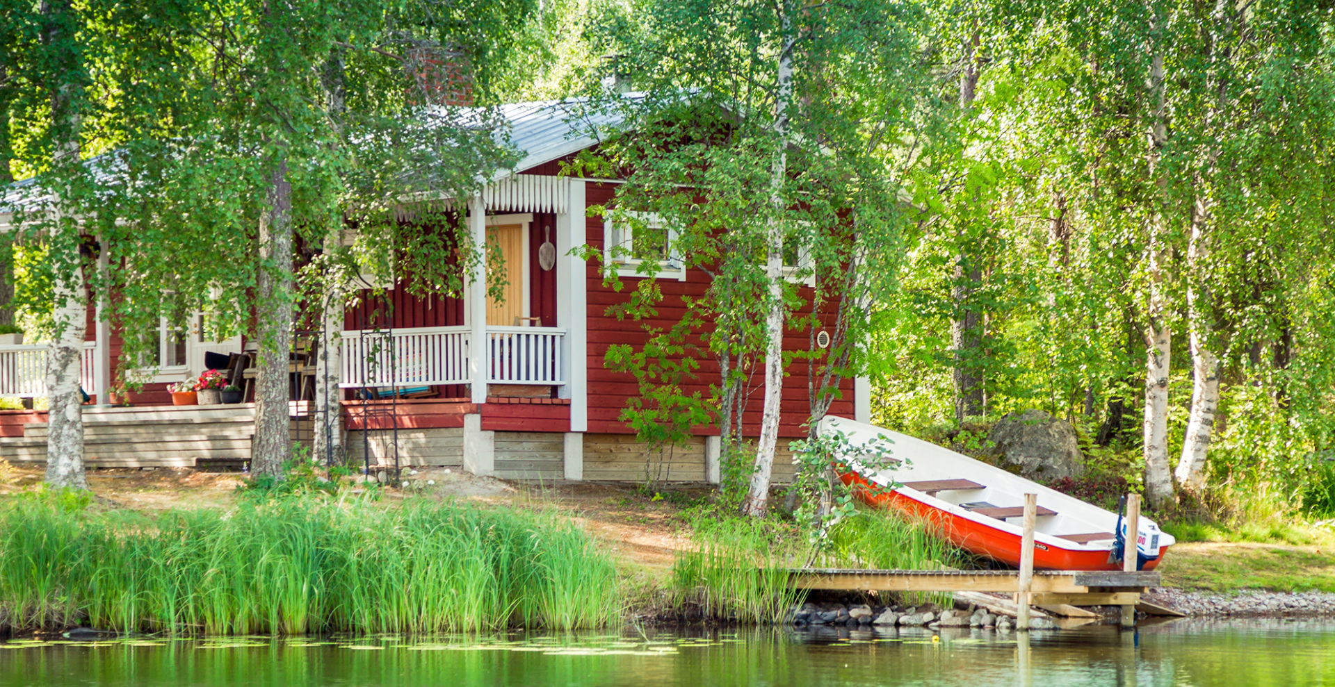 punainen kesämökki järven rannalla