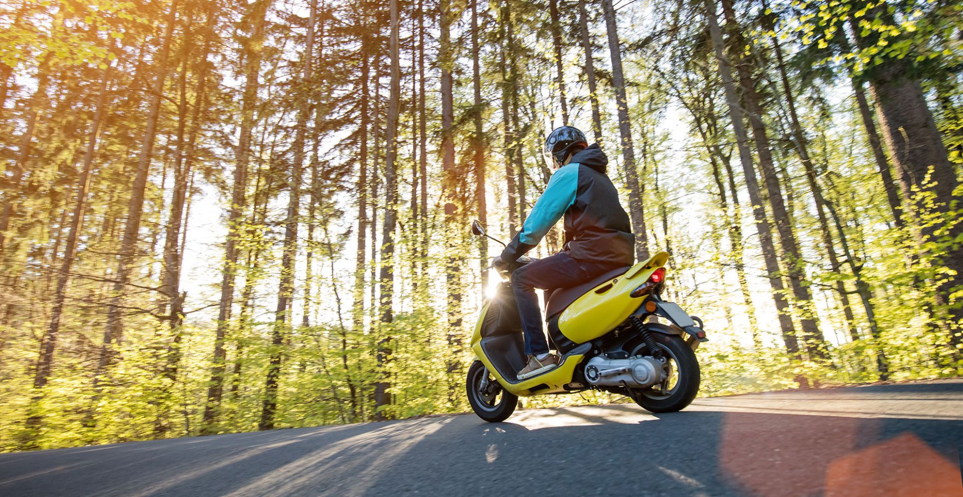 nuori henkilö ajaa skootterilla metsätiellä