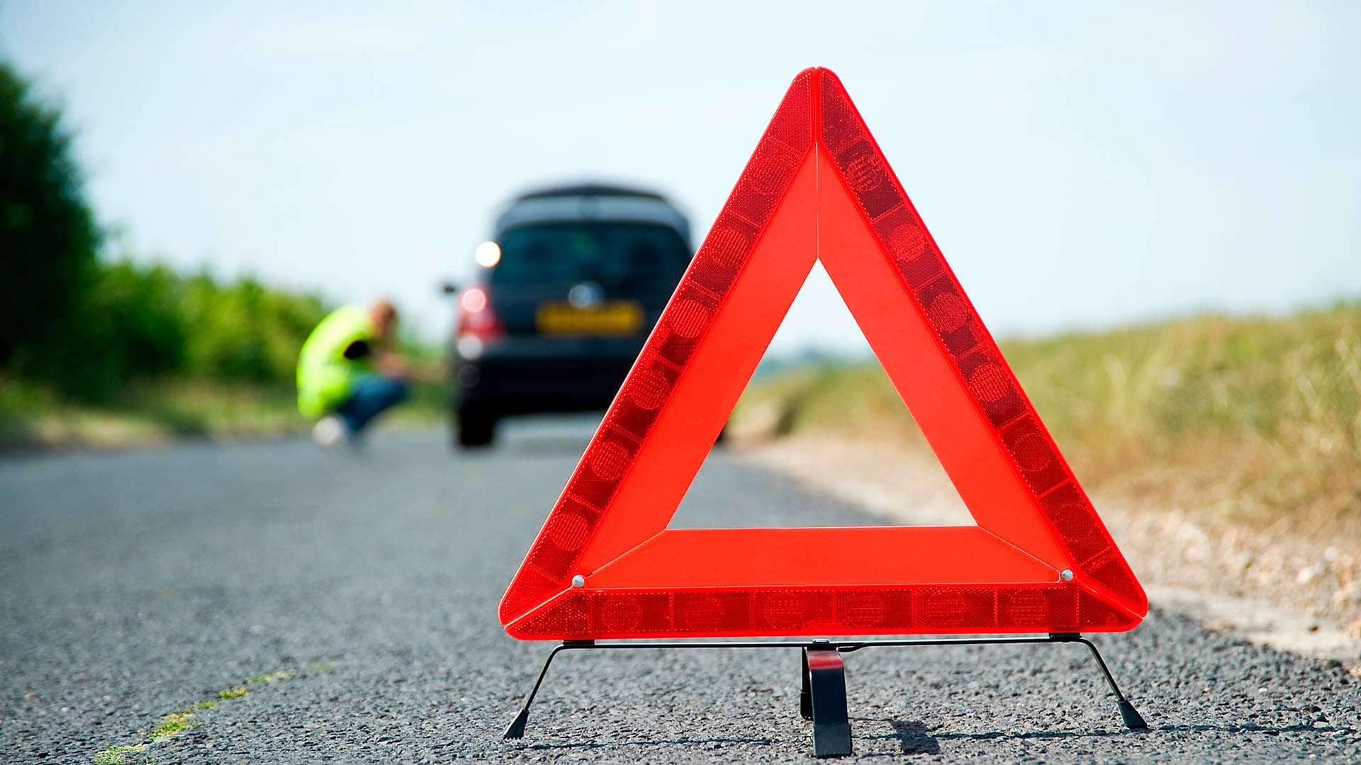 Turvallisuusvälineet. Varoituskolmio varoittamassa tielle jääneestä autosta.