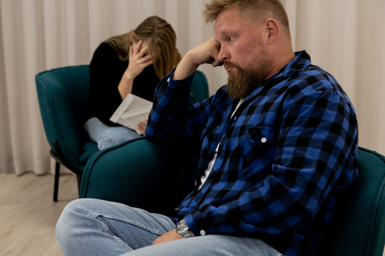 Mies ja nainen istuvat vierekkäin ja nojaavat käsiinsä.